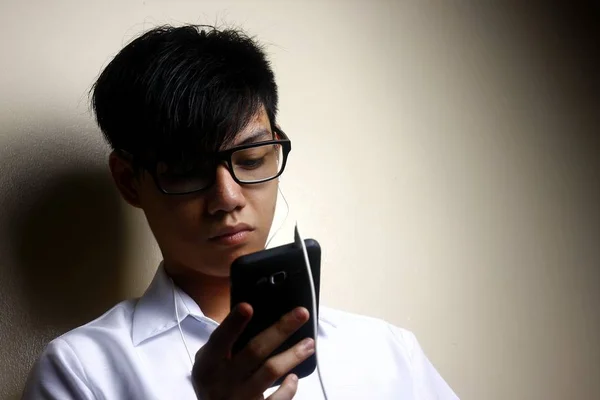 Teen using a smartphone with an earphone — Stock Photo, Image