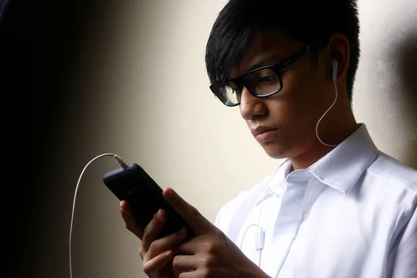 Teen using a smartphone with an earphone — Stock Photo, Image