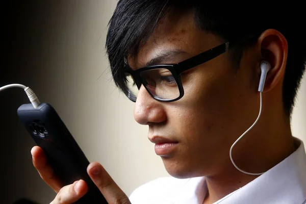 Adolescent utilisant un smartphone avec un écouteur — Photo