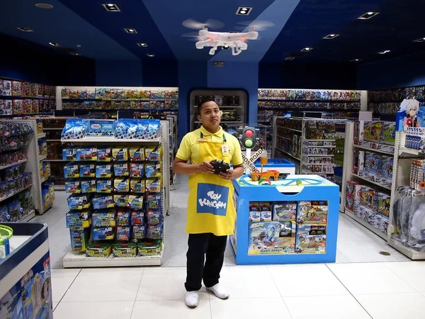 Un empleado de una juguetería demuestra cómo volar un dron de juguete . — Foto de Stock