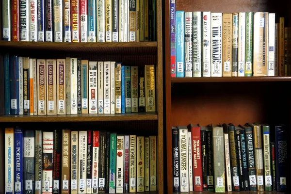 A wide variety of books on wooden shelves inside a library. — Stock Photo, Image