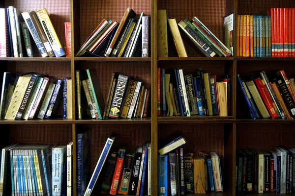 A wide variety of books on wooden shelves inside a library. — Stock Photo, Image