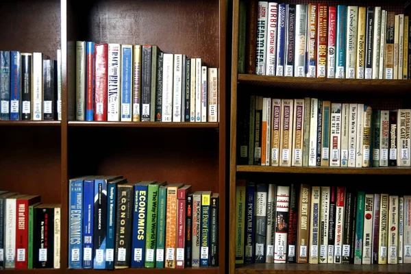 Una amplia variedad de libros en estantes de madera dentro de una biblioteca . —  Fotos de Stock