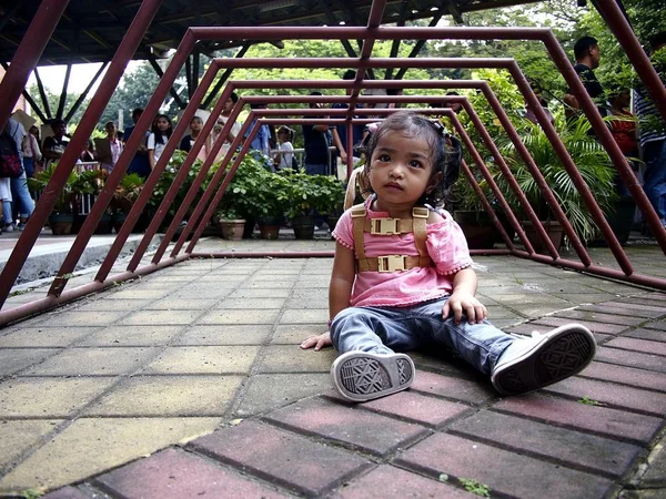 Una niña jugando debajo de un estante de estacionamiento de bicicletas . —  Fotos de Stock