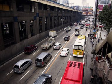 Private and public vehicles passing along EDSA and the Boni MRT Station in Mandaluyong City, Philippines. clipart