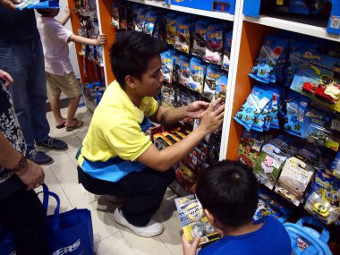 Bir oyuncak mağaza çalışanı çocuklar için oyuncak araba bakmak yardımcı olur..