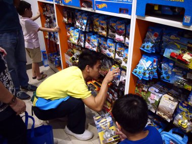 Bir oyuncak mağaza çalışanı çocuklar için oyuncak araba bakmak yardımcı olur..