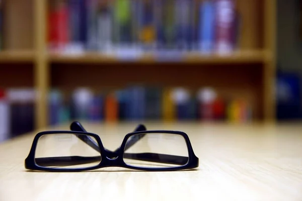 Pair of eyeglasses on a library table — Stock Photo, Image