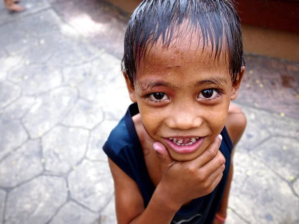 Un jeune garçon sourit pour la caméra après s'être mouillé à une fontaine d'eau dans un parc extérieur . — Photo