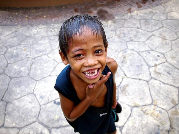 En ung gutt smiler til kameraet etter å ha blitt våt ved en fontene i en utendørs park. . – stockfoto