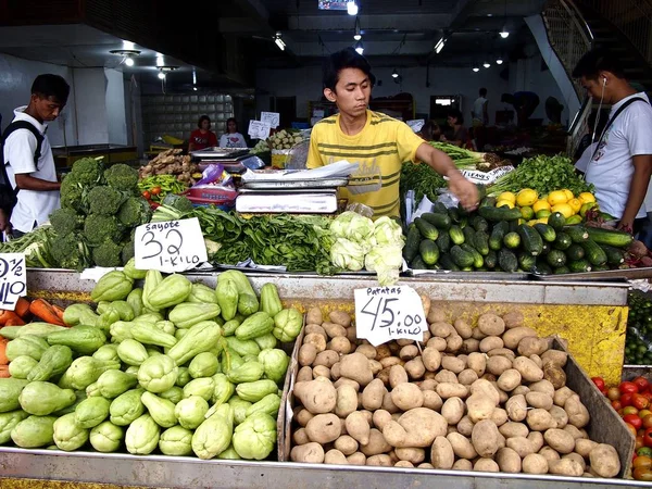 A vendor sells fresh vegetable in a store at a public market. — Stock Photo, Image