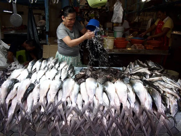 Un vendedor vende pescado fresco y otros productos del mar en una tienda en un mercado público . —  Fotos de Stock