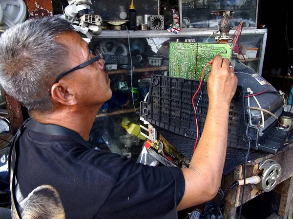 Un electricista repara un viejo televisor en su taller . —  Fotos de Stock