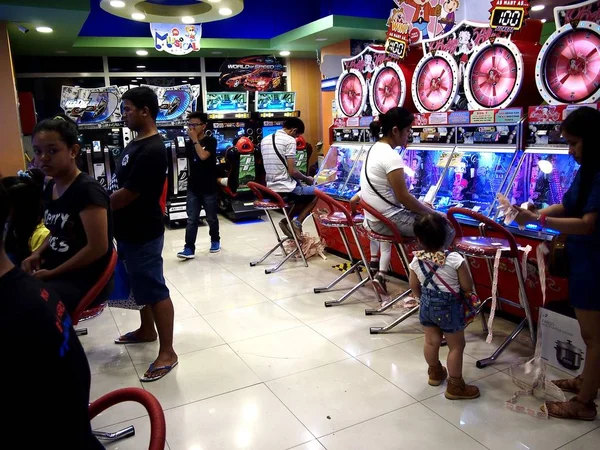 Los clientes disfrutan de los diferentes juegos y atracciones dentro de una galería de atracciones en un centro comercial . — Foto de Stock