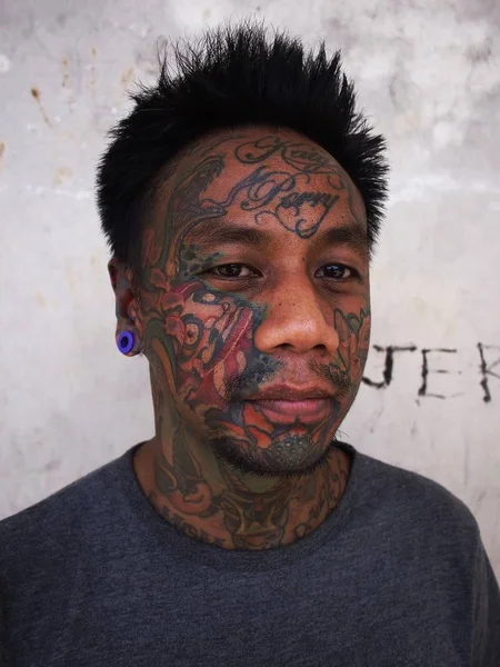 Un homme avec de l'art corporel montre son tatouage facial et son perçage d'oreille . — Photo