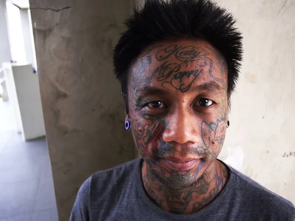 Un homme avec de l'art corporel montre son tatouage facial et son perçage d'oreille . — Photo