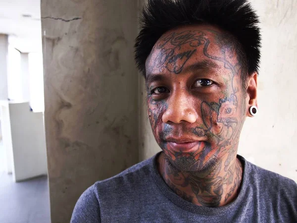 Un homme avec de l'art corporel montre son tatouage facial et son perçage d'oreille . — Photo