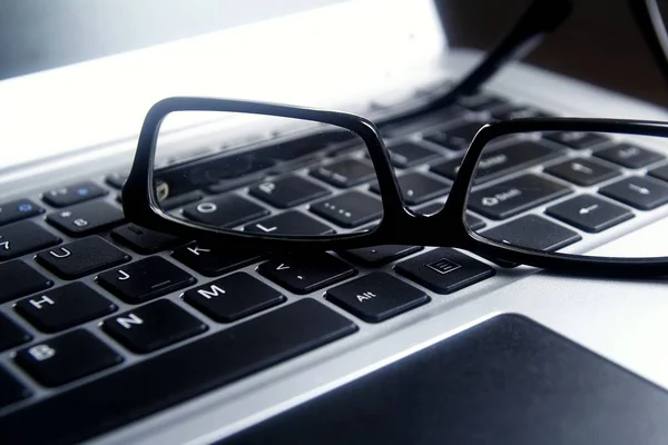 Gafas graduadas en un teclado de ordenador portátil — Foto de Stock