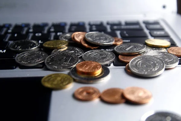 Monedas en un teclado de computadora portátil —  Fotos de Stock