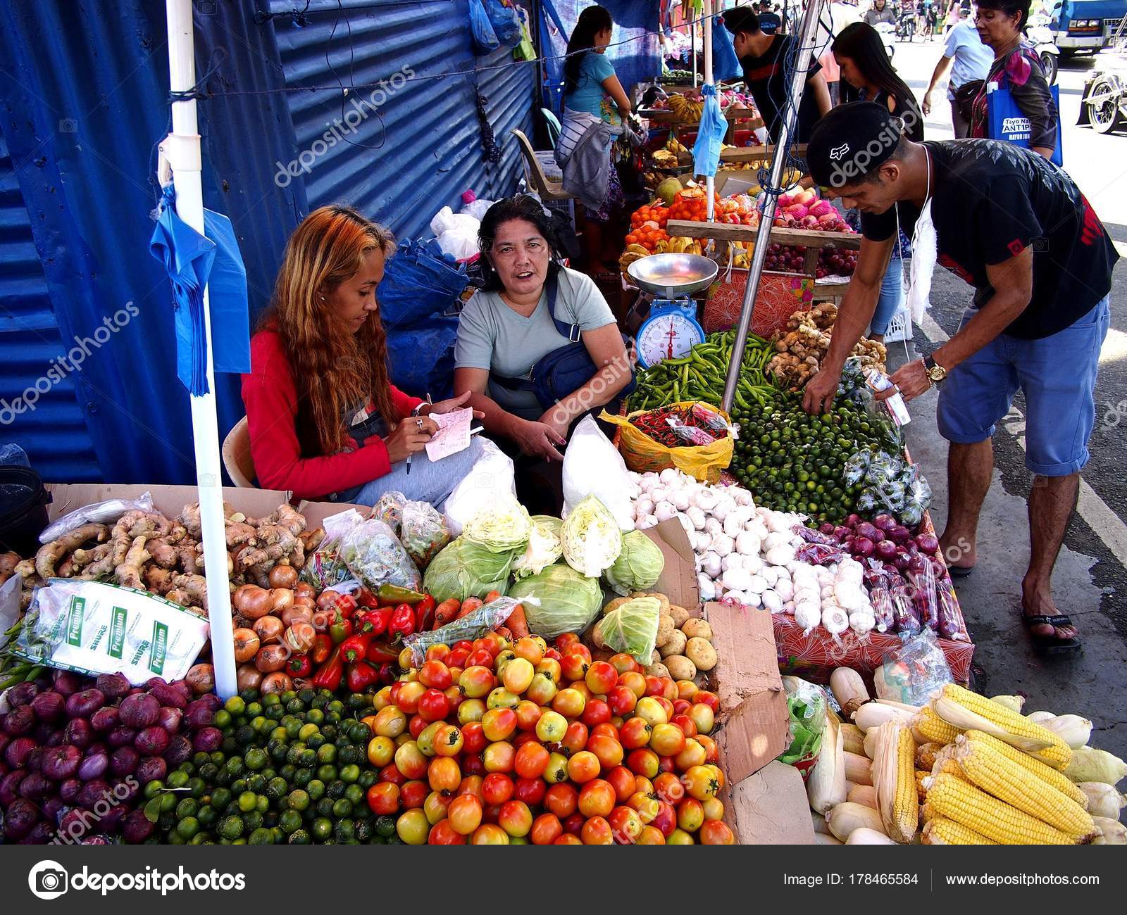 Street vendors sell assorted fresh fruits and vegetables along a busy Street vendors sell assorted fresh fruits and vegetables along a busy