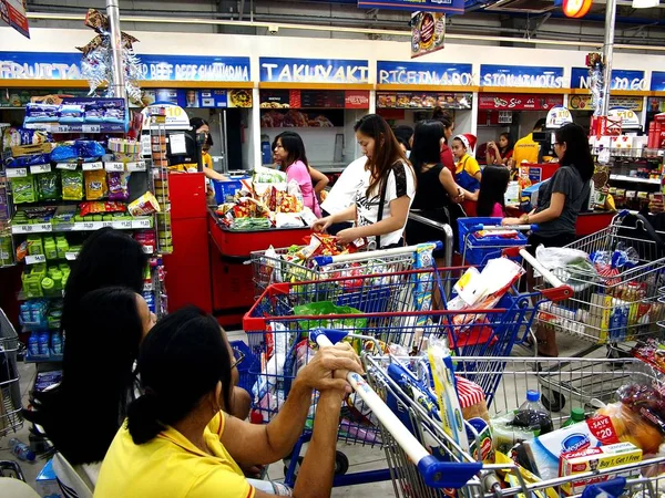 Los clientes hacen cola para el cajero en una tienda de comestibles . — Foto de Stock