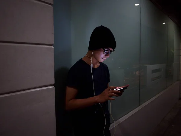 Adolescente usando um smartphone lá fora à noite — Fotografia de Stock