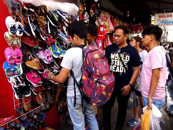 Os clientes olham e escolhem entre diferentes sapatos infantis em uma loja de turnos por uma calçada . — Fotografia de Stock