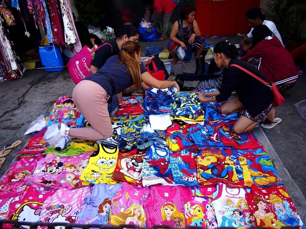 Customers look and choose among different clothing products at a make shift store by a sidewalk. — Stock Photo, Image