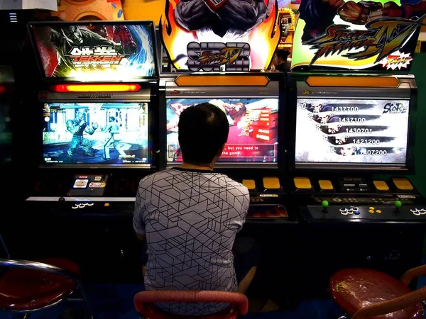 Klanten genieten van de verschillende spellen en attracties binnen een amusement arcade in een winkelcentrum. — Stockfoto