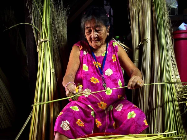 Uma senhora idosa apara folhas de coco para serem usadas como embalagem para uma iguaria local chamada Suman ou arroz glutenoso cozido no vapor. . — Fotografia de Stock