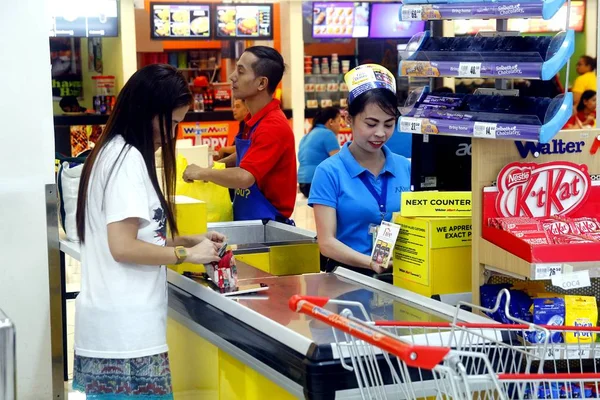 Un cajero atiende a un cliente en una tienda de comestibles . — Foto de Stock