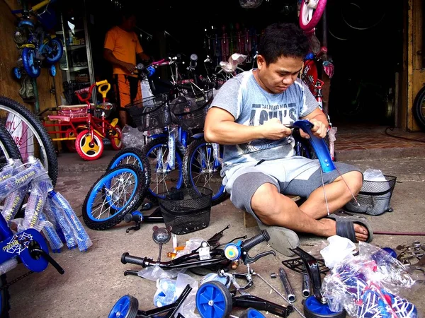 Ein Mitarbeiter eines Fahrradgeschäfts repariert ein Fahrrad für einen Kunden — Stockfoto