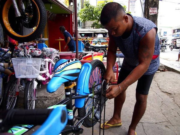 Um funcionário de uma loja de bicicletas corrige uma bicicleta para um cliente — Fotografia de Stock