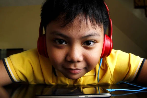 Unga asiatiska pojke med en smartphone och hörlurar — Stockfoto
