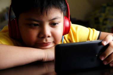 Bir akıllı telefon ve kulaklık ile genç Asyalı çocuk