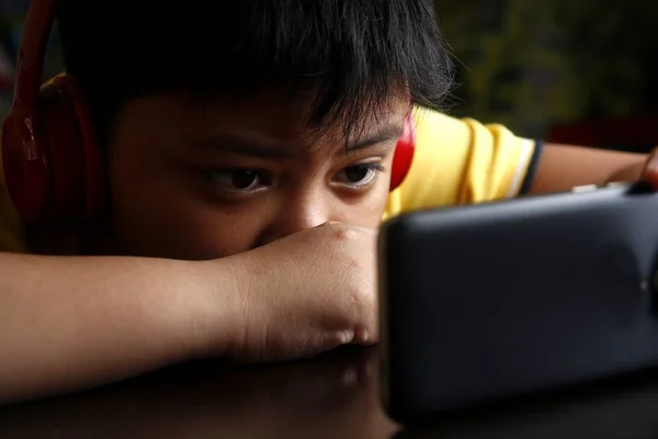 Young Asian boy with a smartphone and headphones — Stock Photo, Image