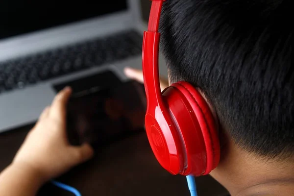 Young Asian boy with a smartphone and headphones — Stock Photo, Image