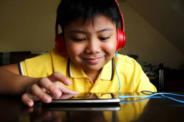 Jovem menino asiático com um smartphone e fones de ouvido — Fotografia de Stock