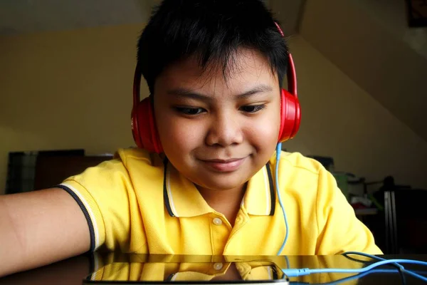 Young Asian boy with a smartphone and headphones — Stock Photo, Image