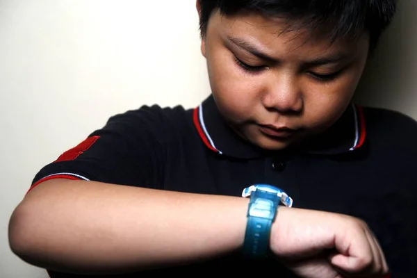 Joven chico asiático mirando su reloj de pulsera — Foto de Stock