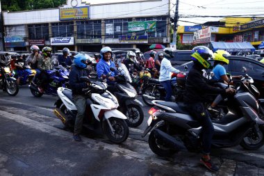 Motosiklet sürücüleri sıkışık ve yoğun bir kavşakta durup sıralarının gelmesini beklerler..