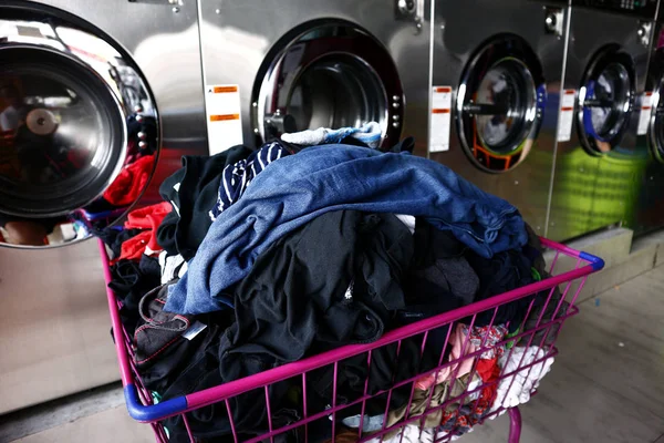 Bande de blanchisserie propre dans un panier devant les machines à laver — Photo