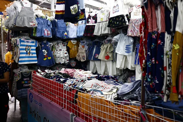 Roupas acessíveis sortidas e calçado em exposição em uma barraca de bazar — Fotografia de Stock