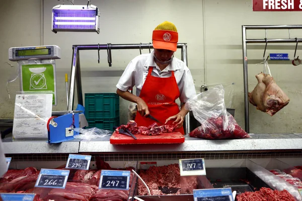 Il dipendente del supermercato taglia la carne fresca per un cliente nella sezione carne del negozio . — Foto Stock