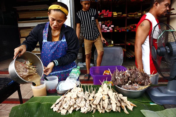 Vendedor ambulante se prepara para cocinar una variedad de comida callejera en una tienda improvisada en una acera . —  Fotos de Stock