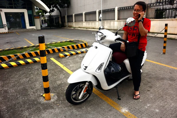 Mujer motociclista se detiene en una acera para el usuario de su teléfono inteligente — Foto de Stock