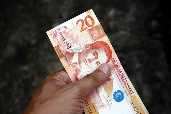 Hand holding twenty Philippine peso bill and a road as background — Stock Photo, Image