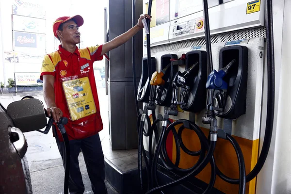 Mitarbeiter einer Tankstelle betätigt die Zapfsäule, um das Auto eines Kunden zu betanken. — Stockfoto
