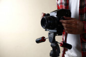Dospělý muž drží starý a vintage střední formát filmové kamery na stativu.