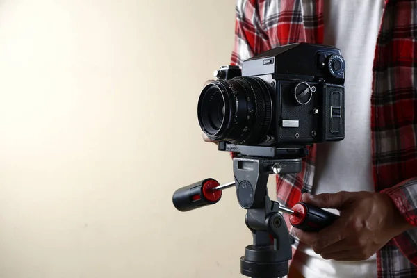 Felnőtt férfi kezében egy régi és vintage közepes formátumú film kamera egy állvány. — Stock Fotó